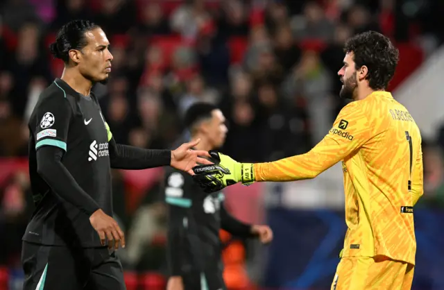 Virgil van Dijk of Liverpool interacts with teammate Alisson Becker