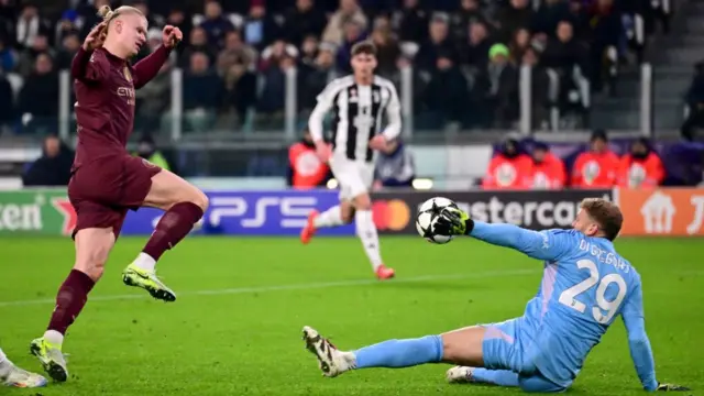 Michele Di Gregorio (R) saves a shot from Manchester City's Norwegian forward #09 Erling Braut Haland