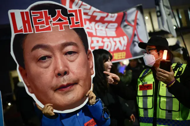 A protester holds a placard bearing Yoon's face