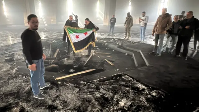 Rebels stand in the middle of a charred room