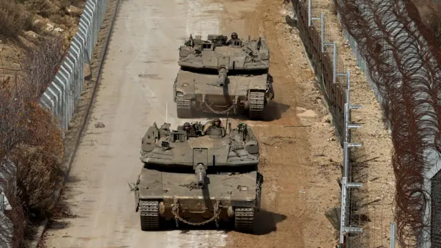 Israeli tanks drive between fences as troops move within the buffer zone between Israel and Syria, near the Druze village of Majdal Shams, in the Israeli-annexed Golan Heights, 10 December 2024