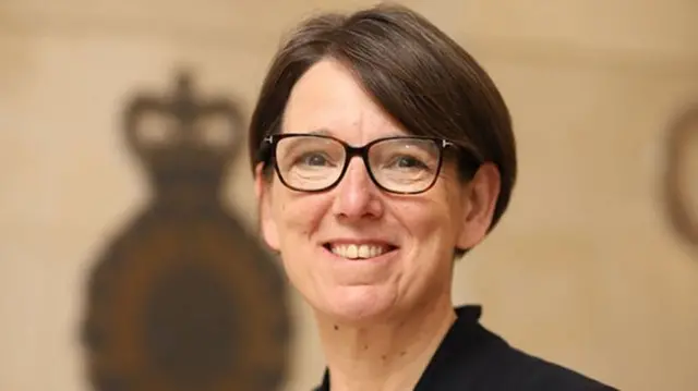 Anne Keast-Butler wearing a black suit and tortoise rimmed glasses