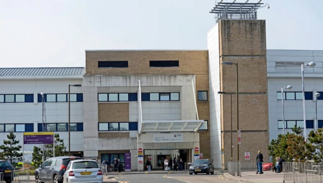 The outside of the Royal Infirmary of Edinburgh, with a number of cars and pedestrians.