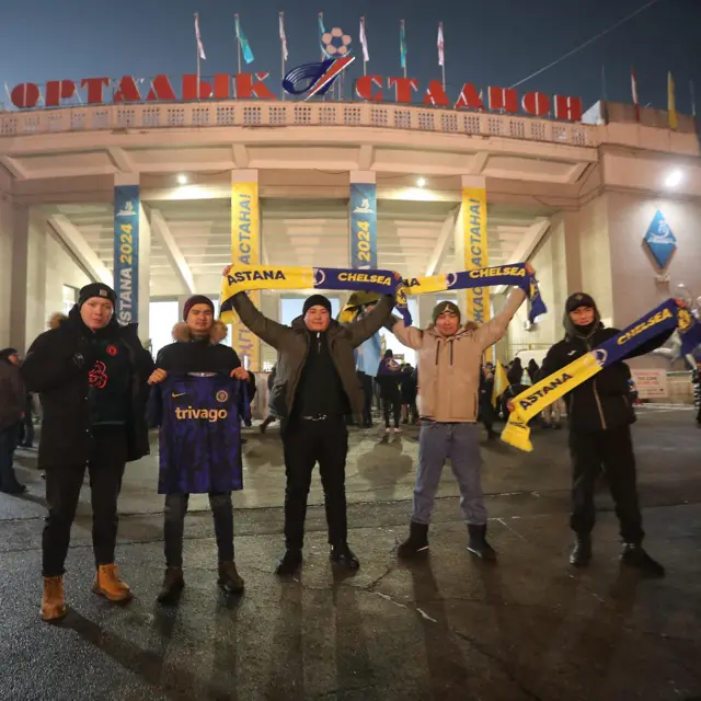 Fans hold up half and half scarves outside the Almaty Arena
