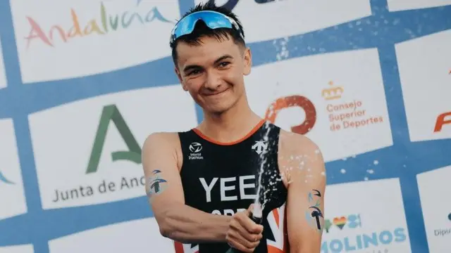 Alex Yee pops a champagne cork on the podium after winning the world triathlon title