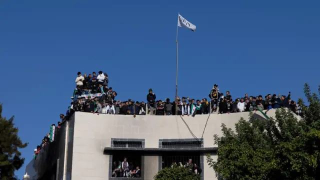 People watch a rally in Latakia from a packed rooftop