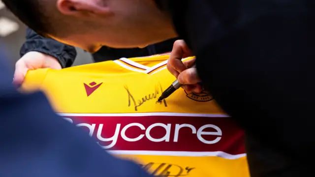 Motherwell midfielder Lennon Miller signs a shirt for a supporter