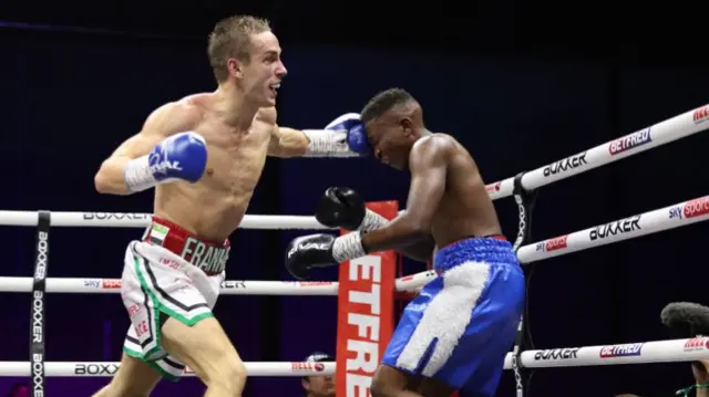 Frankie Stringer punching his opponent and forcing him back towards the ropes