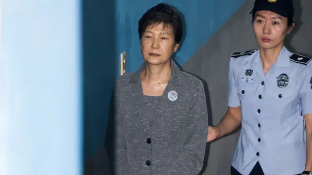 Park Geun-hye is escorted by a prison officer as she arrives at the Seoul Central District Court in August 2017