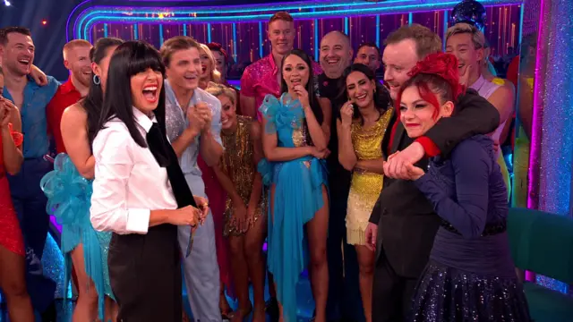 Presenter Claudia Winkleman laughing along with professionals, while Chris has his arm around partner Dianne