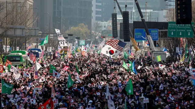 A crowd waving Korean and American flags on the road