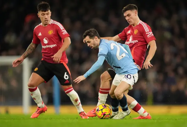 Manchester City's Bernardo Silva and Manchester United's Manuel Ugarte battle for the ball