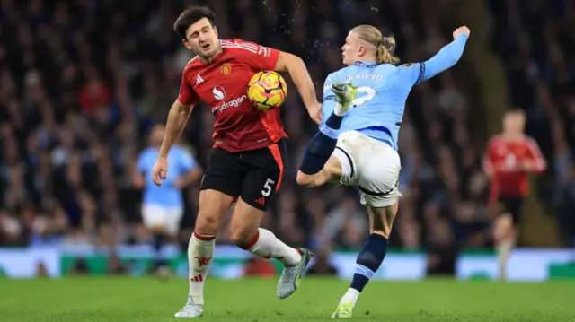 Harry Maguire of Manchester United and Erling Haaland of Manchester City compete for the ball