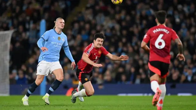 Harry Maguire of Manchester United heads the ball whilst under pressure from Erling Haaland