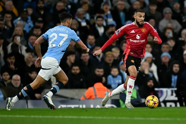 Manchester United defender Noussair Mazraoui runs with the ball from Manchester City midfielder Matheus Nunes