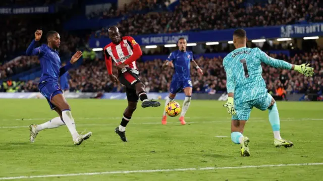 Yoane Wissa of Brentford misses a chance whilst under pressure from Robert Sanchez of Chelsea