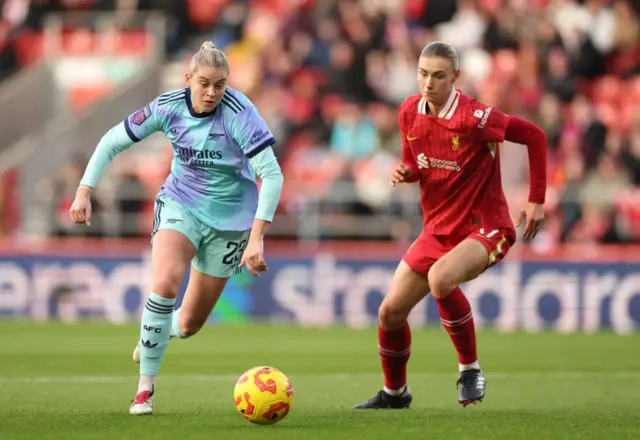 Alessia Russo of Arsenal runs with the ball whilst under pressure from Jenna Clark