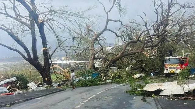 A rescue worker attempts to clear a fallen tree from blocked road, in the aftermath of the Cyclone Chido, within Mamoudzou in Mayotte, France, December 15,