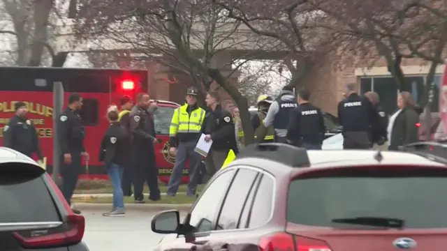 Police officers stand on the pavement next to parked vehicles