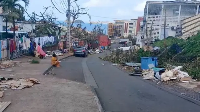 A person sits on the curb in the aftermath of Cyclone Chido, in Mamoudzou, Mayotte