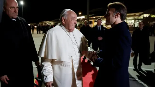 Pope Francis shakes hands with France's President Emmanuel Macron during the Pope's departure ceremony at the Ajaccio airport, on the French island of Corsica