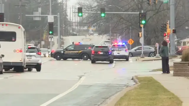 Police cars on the road next to the school with their sirens on