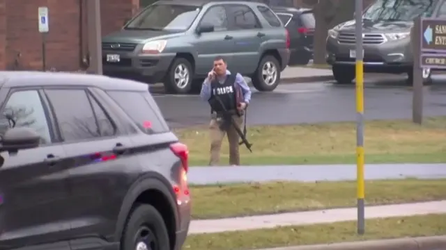 A policeman holds a gun outside a school in Wisconsin