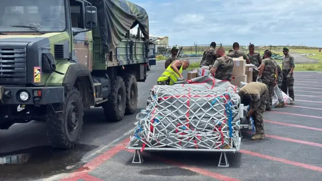 Uniformed army personnel sort through boxes of aid on a roadside