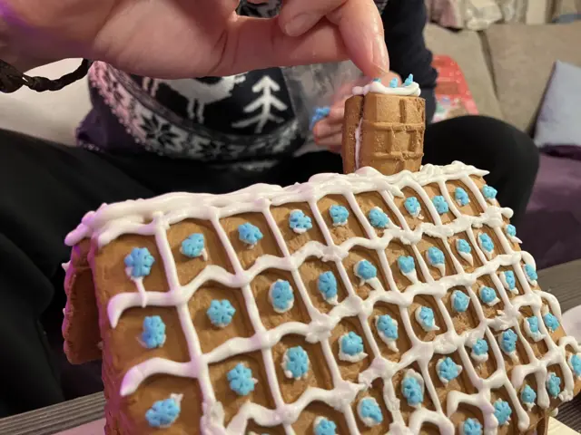 A gingerbread house roof with white icing and blue snowflakes