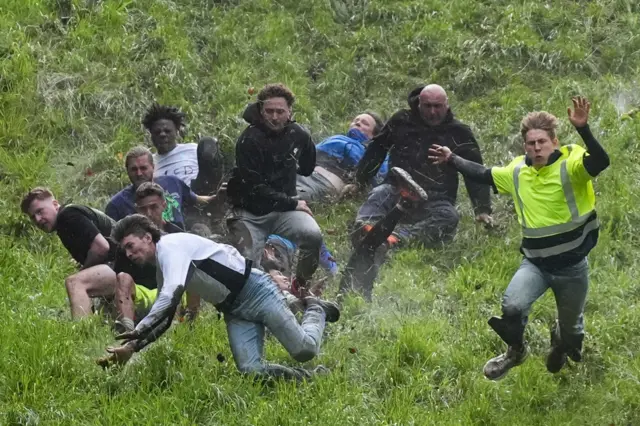 Several men roll and fall down a hill