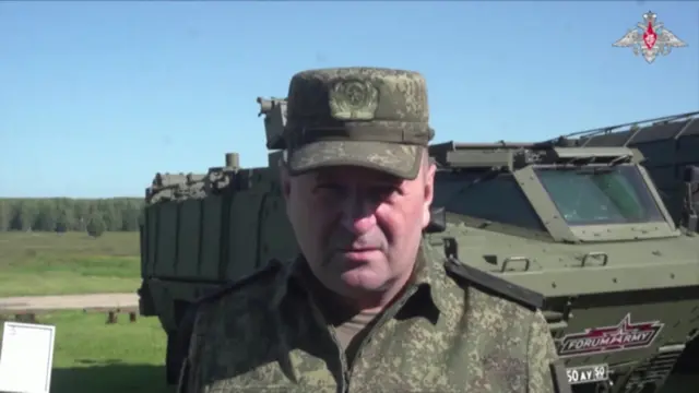 Kirillov wearing army uniform and facing the camera. An army vehicle is in the background