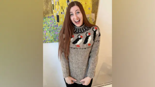 Woman in a grey jumper with puffin pattern smiling