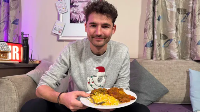 Charlie Taylor holding a plate with a curry on