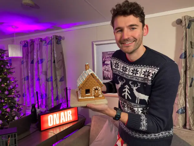 Charlie Taylor holding a gingerbread house he's decorated