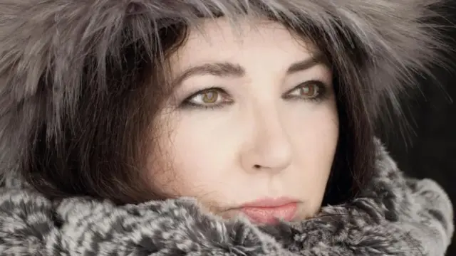 Kate Bush in a grey hat and scarf looking into the distance