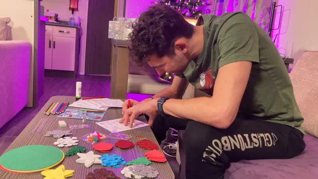 Charlie Taylor using a pencil to colour in a Christmas card