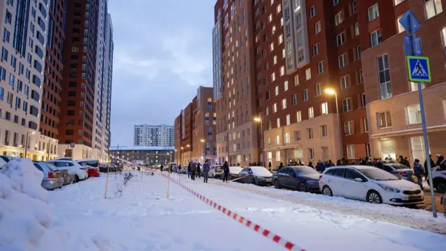 A wide view shot of a street in Moscow with high-rise buildings and snow on the ground