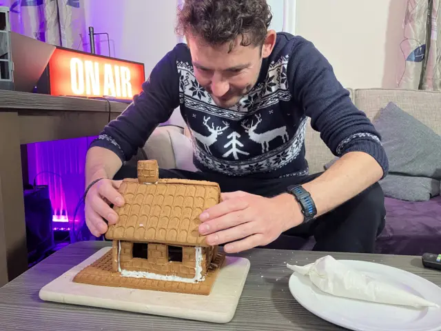 Charlie Taylor putting the roof on a gingerbread house