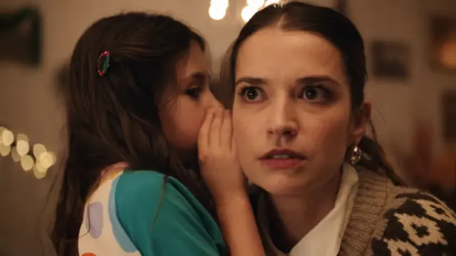 A little girl whispering to a woman, as part of a scene from the John Lewis Christmas advert