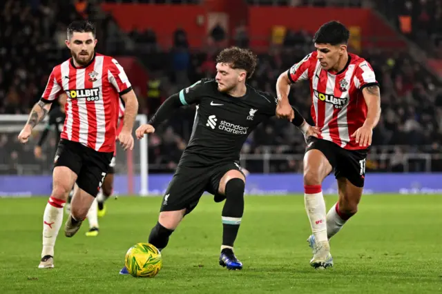 Harvey Elliott of Liverpool is challenged by Mateus Fernandes and Ryan Manning of Southampton