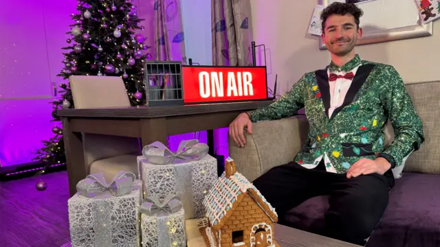 Charlie Taylor sitting on a sofa in a lodge wearing a festive shirt