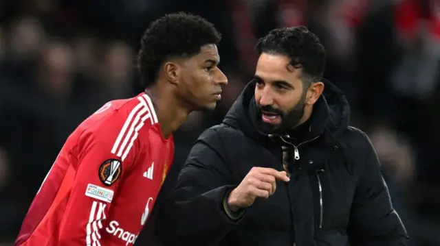 Manchester United head coach Ruben Amorim speaks to Marcus Rashford as he prepares to come on during a Europa League game