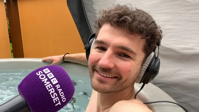 Man in open air hot tub while wearing headphones