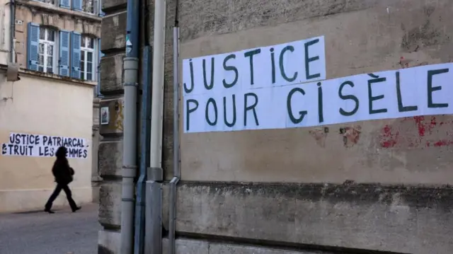 Painted onto a wall in black writing on a white background reads: 'Justice pour Gisele'