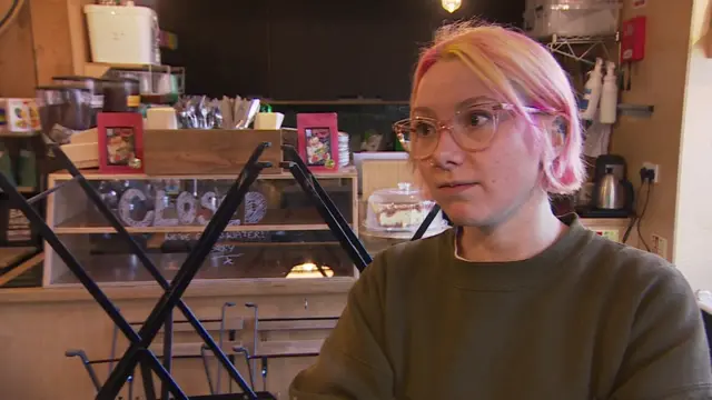 Katie White has pink and blonde hair, pink glasses and a large dark green jumper