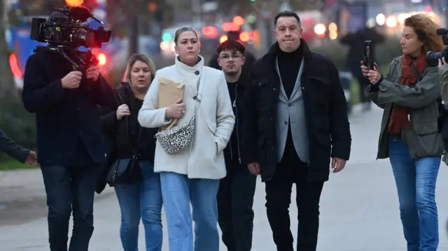 Caroline Darian walks with her brothers towards court