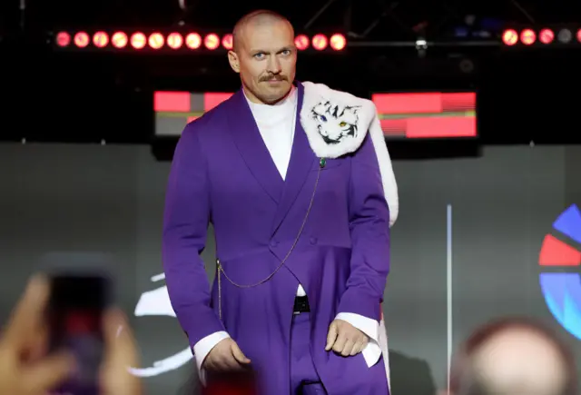 Oleksandr Usyk wearing a purple suit with a white tiger picture on his shoulder