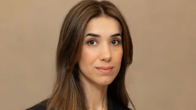 Nobel Peace Price winner Nadia Murad smiling against a brown wall