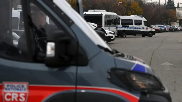 A black van in the foreground with two white vans behind it.