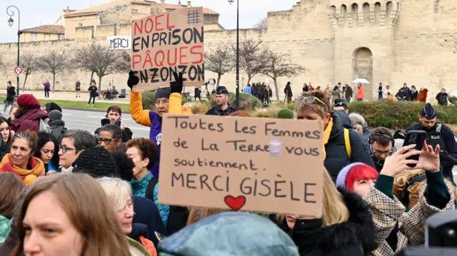 A crowd gathered outside the courthouse, holding up signs in support of Gisèle